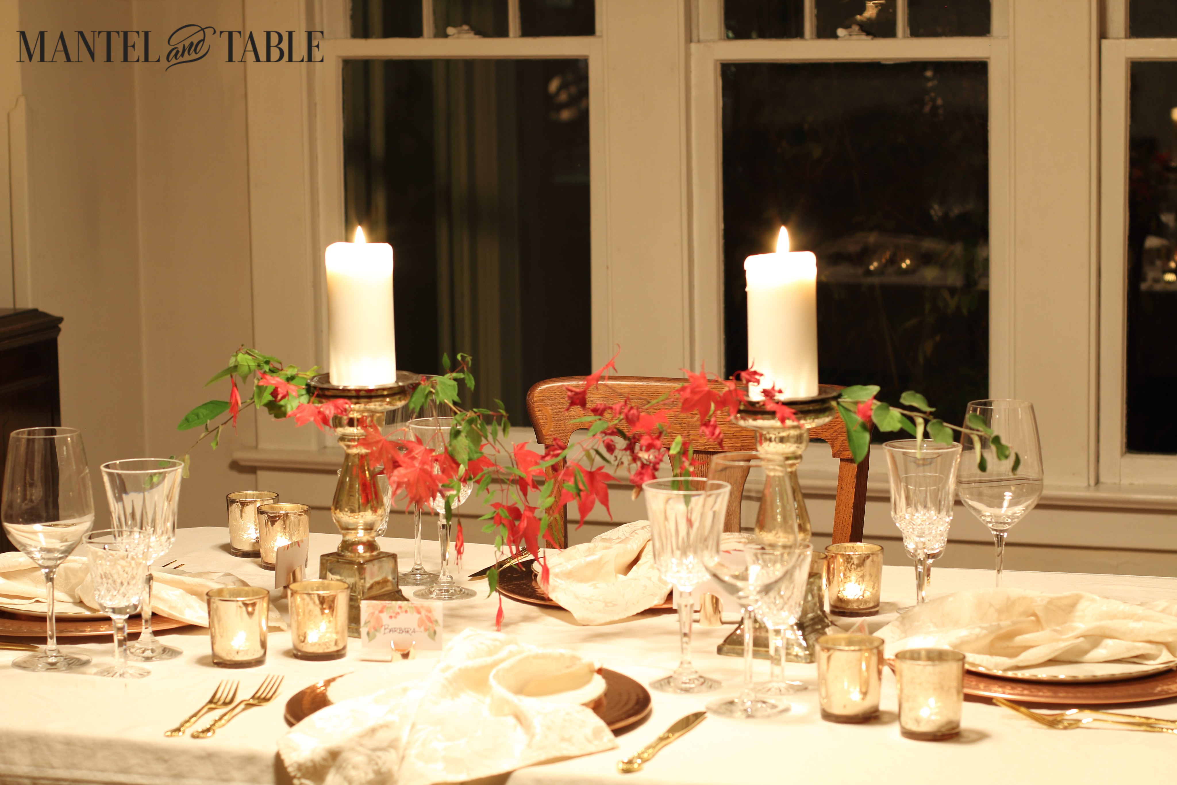 Thanksgiving table with red leaves and fall greenery as a lacy centerpiece draping down from the candlesticks