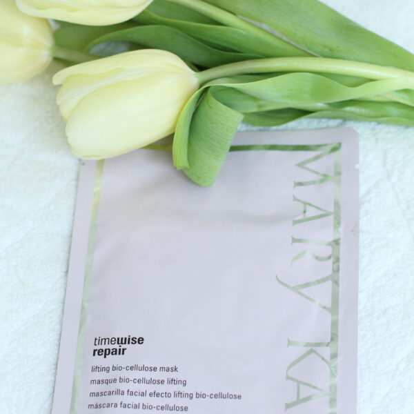 Pink facial mask packet with yellow tulips on white towel