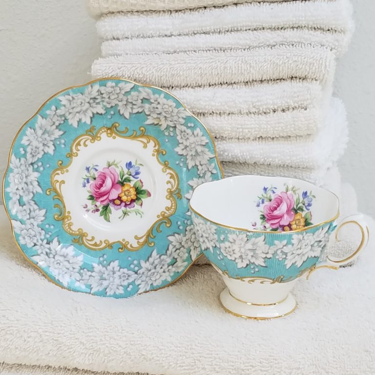 Royal Albert Enchantment Teacup and saucer with a stack of fluffy white towels