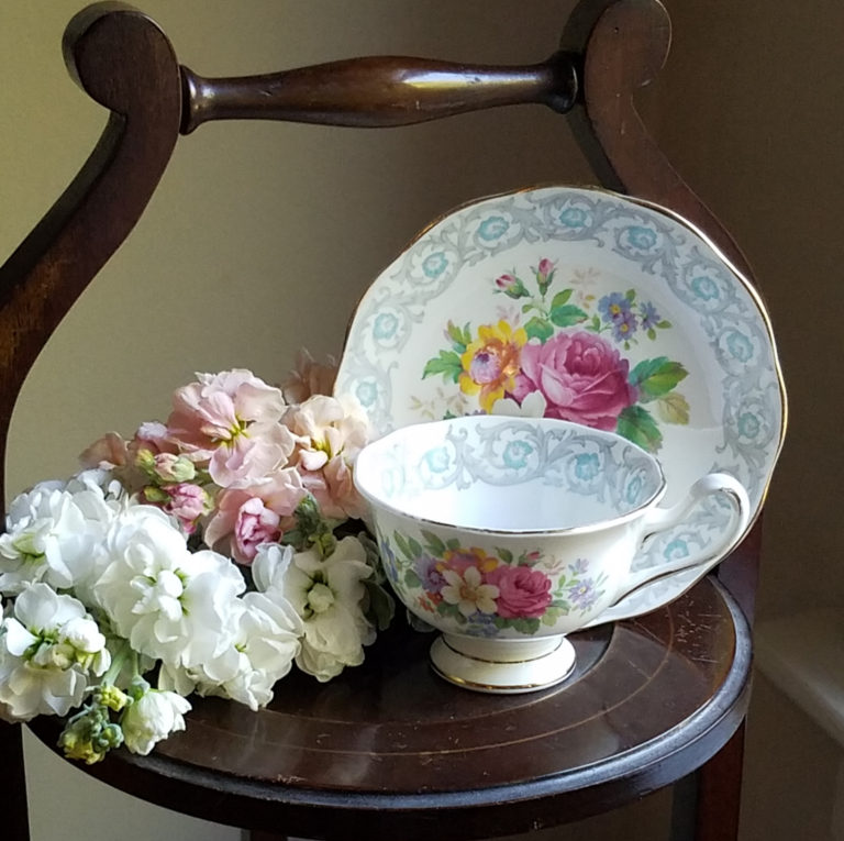My grandmother's teacup resting on a wooden three-tiered tea stand, with white and pink flowers