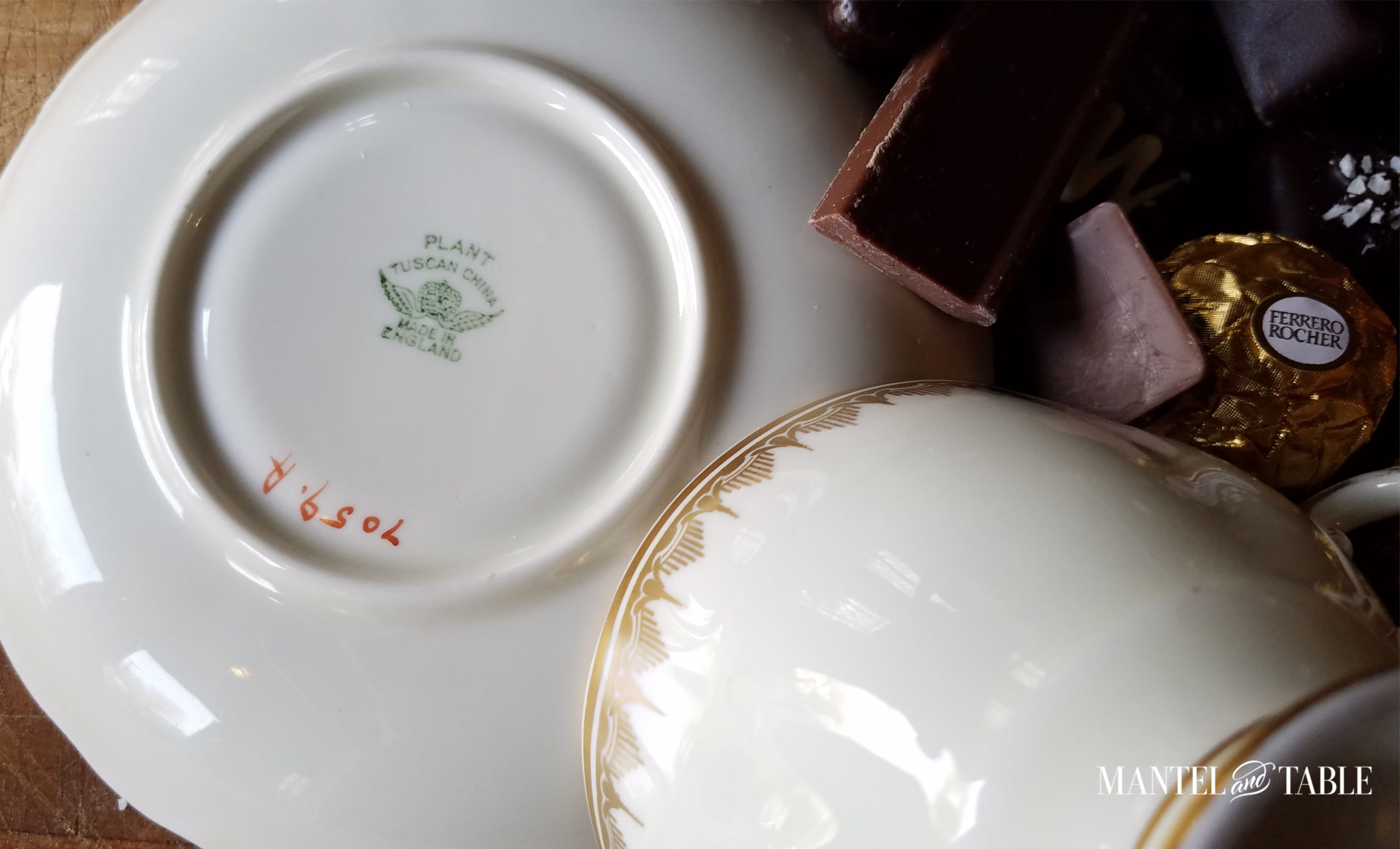 Underside of saucer with overturned cup resting on it. Chocolates beside.