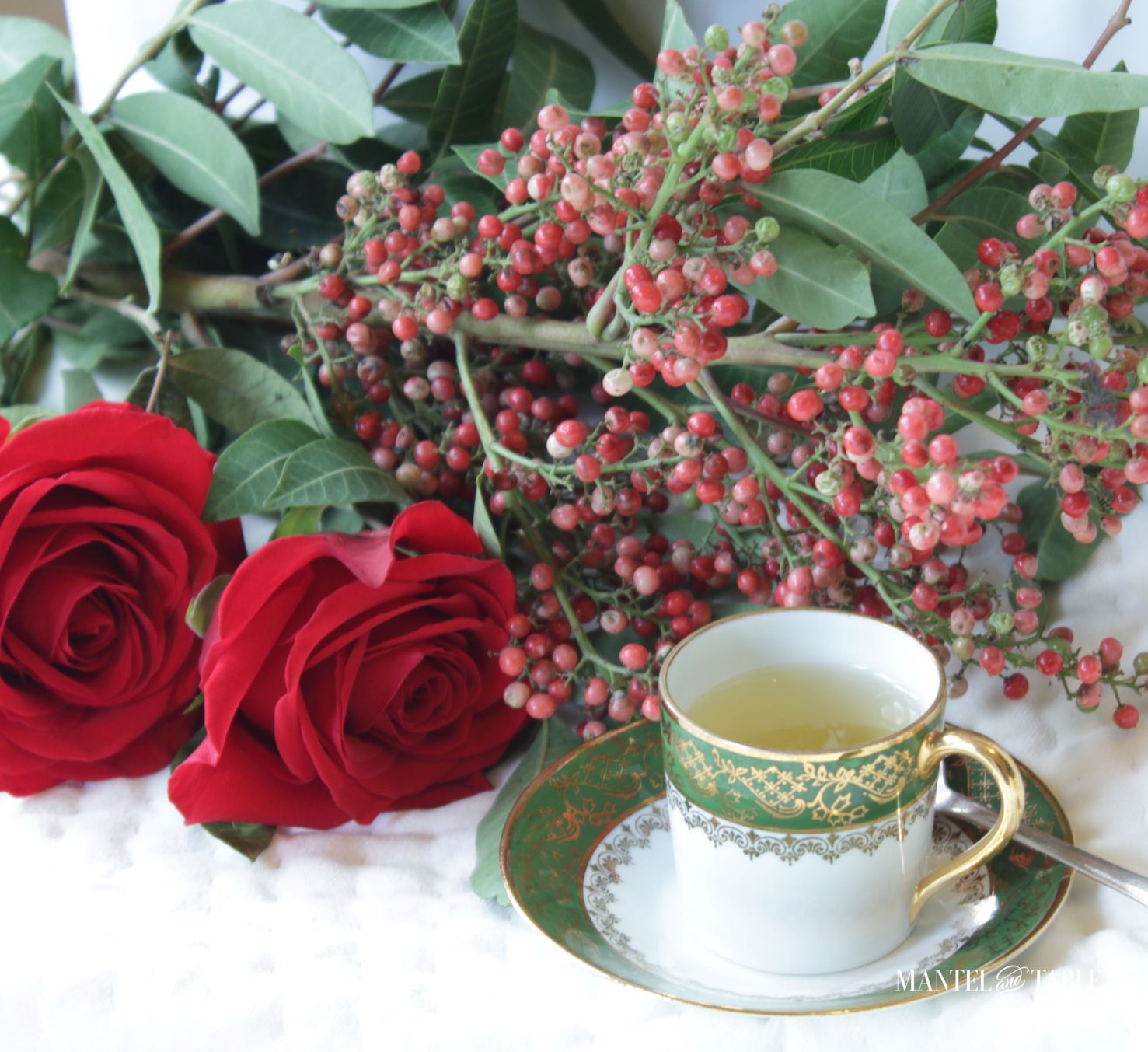 Green and gold teacup with red roses on quilted white