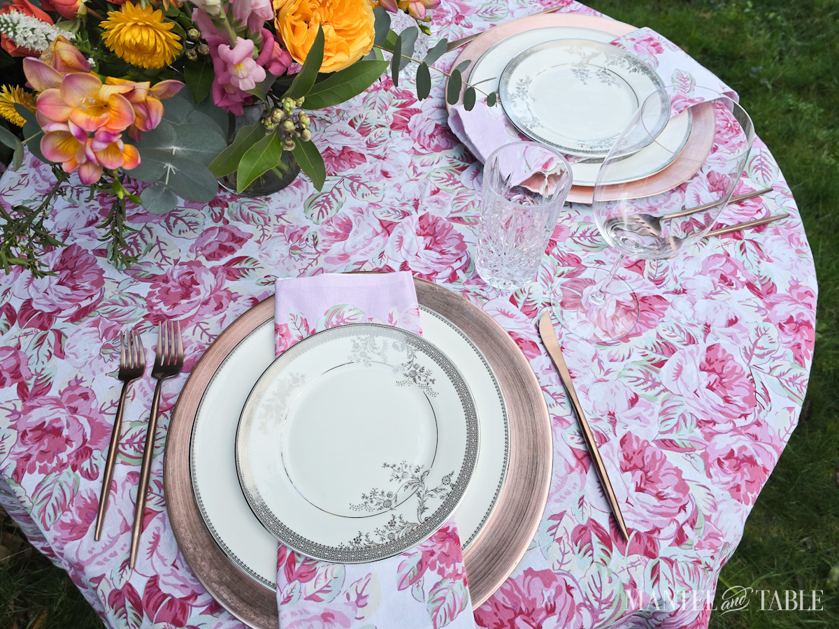 Closeup of two place settings on a floral tablecloth